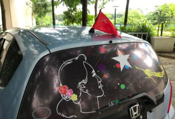 Aung San Suu Kyin kuvat ja NLD:n liput koristavat autoja ja Yangonin katukuvaa