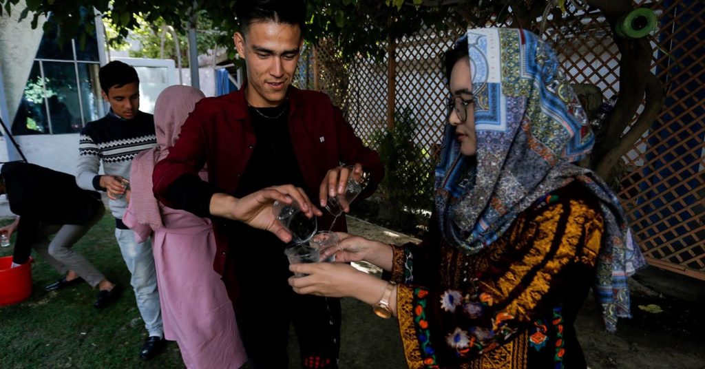 Alyas Rahimi ja Faradis Farhat osallistuivat Kabulissa järjestettyyn työpajaan. Kuvassa nuoret muodostavat pihalla ketjun, jossa osallistujat kuljettavat vettä laseista laseihin. Kuva: Ango