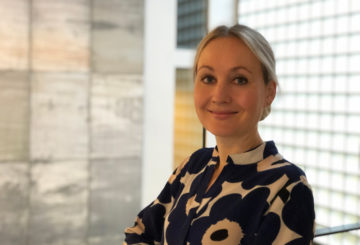 Heini Jurva iförd en Marimekkoblus framför en glasvägg på ambassaden.